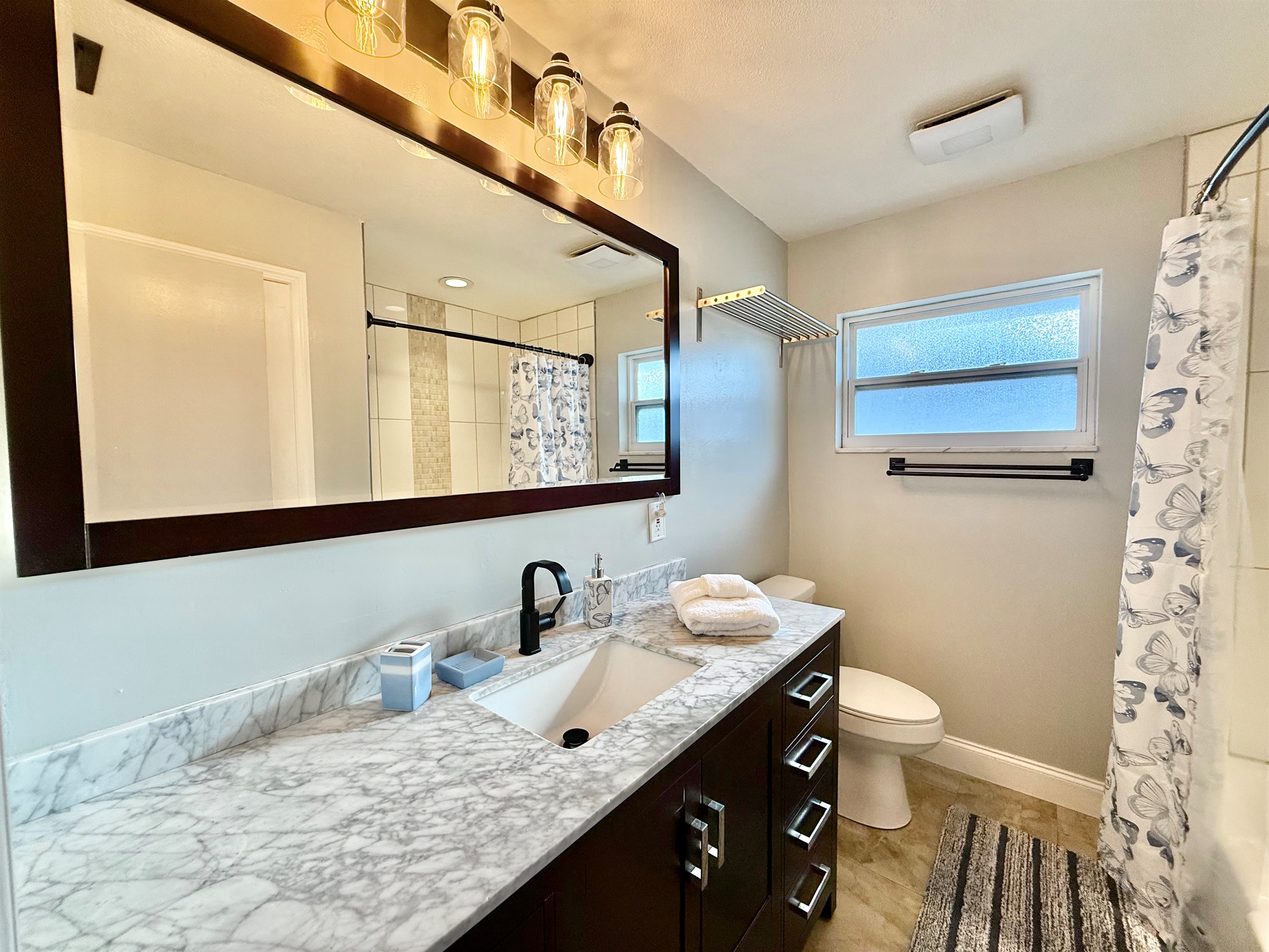 Simple yet inviting, this full bathroom includes a tub and shower combination setup, ample counter space, and a touch of retro character.