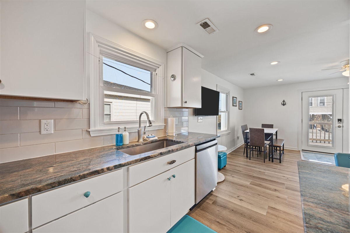 Bright sink area with generous counter space and a clear view toward the dining and deck access