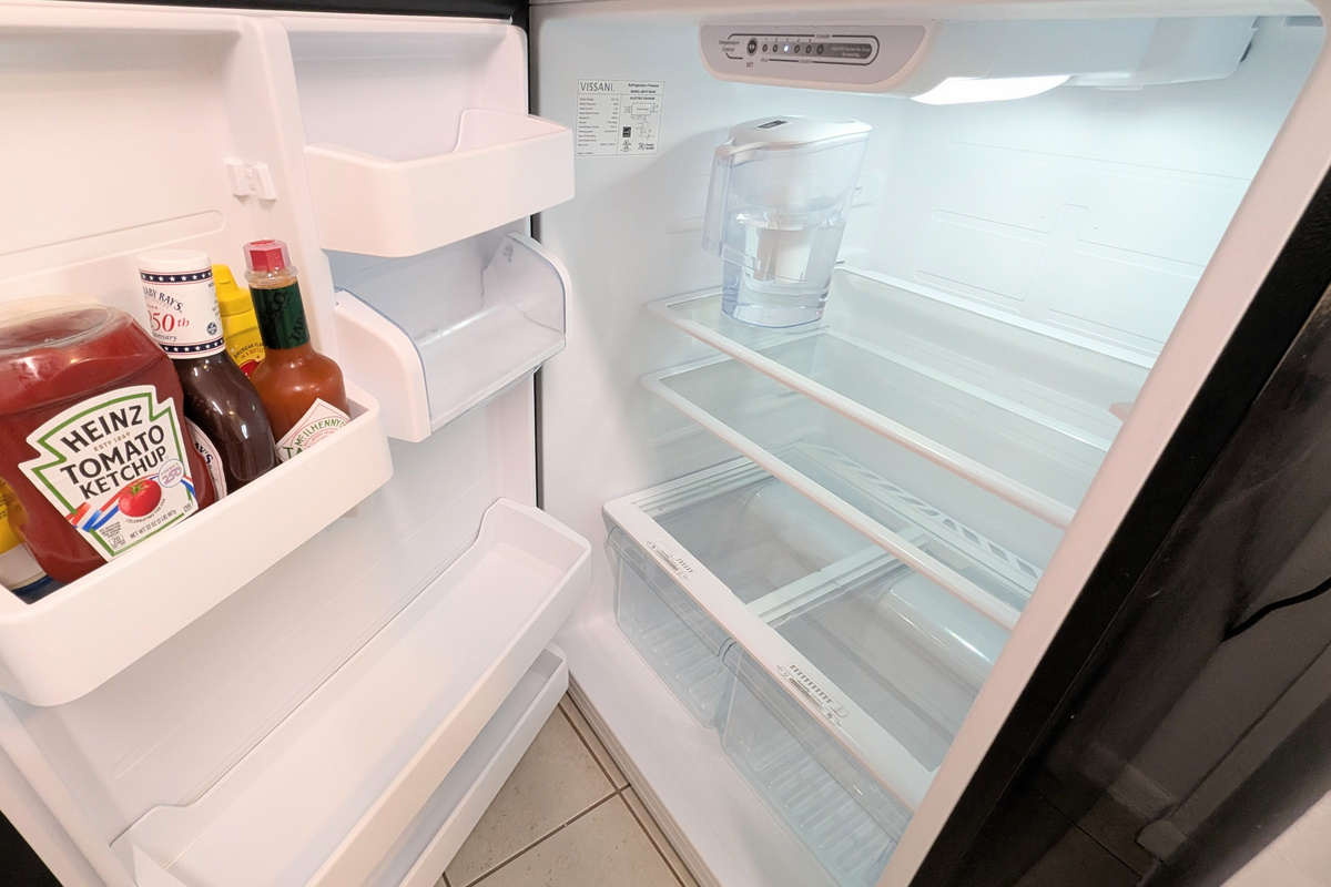 The refrigerator is stocked with filtered water and essential condiments for guests to enjoy.
