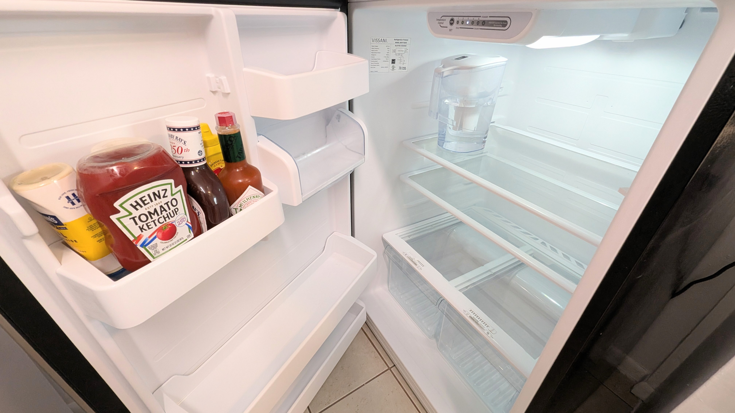 The refrigerator is stocked with filtered water and essential condiments for guests to enjoy.