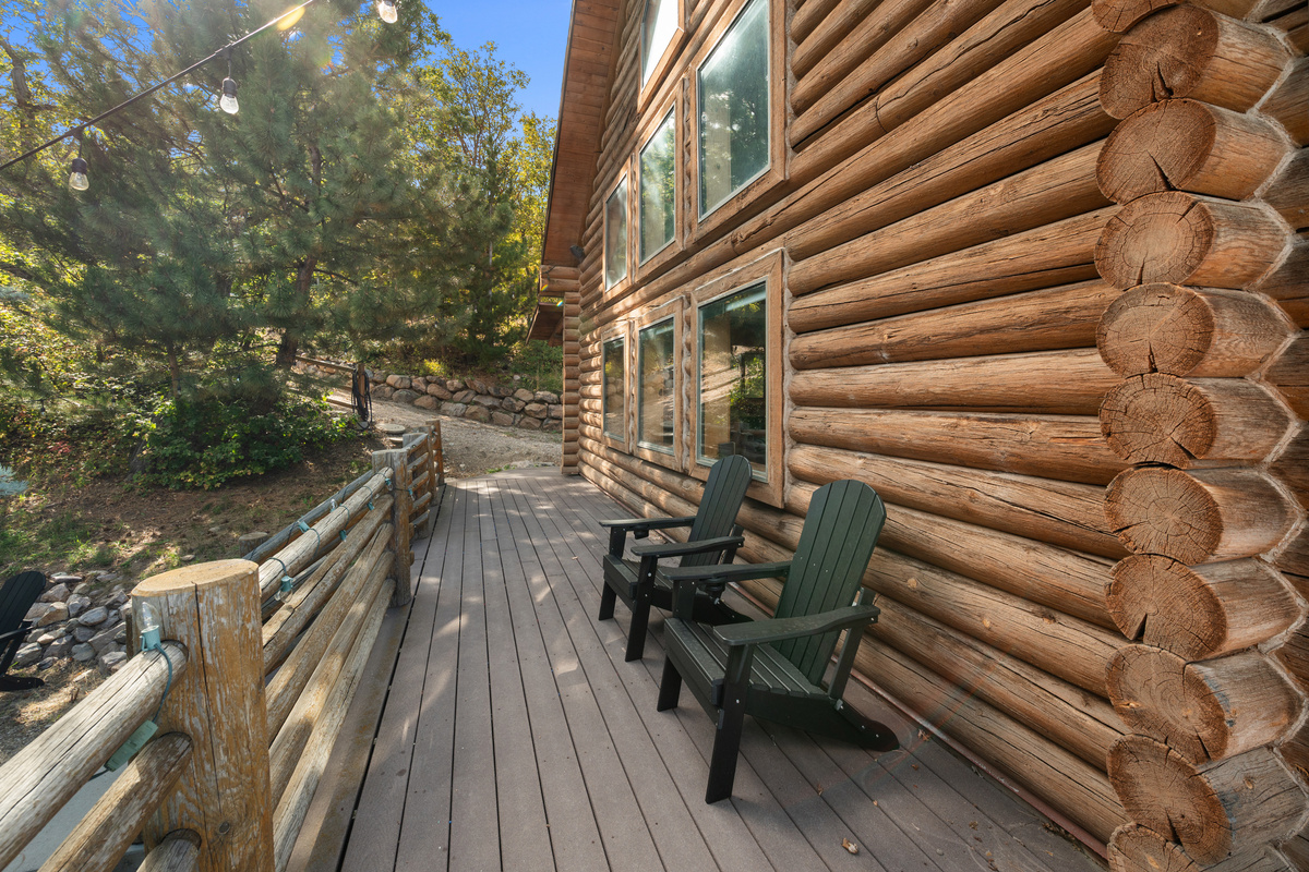 Side deck wraps around the log cabin with peaceful forest surroundings.