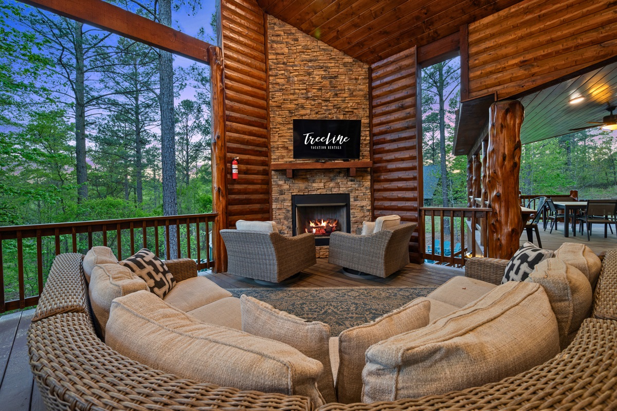 The covered deck features a cozy outdoor living area complete with a fireplace, offering a comfortable place to gather and enjoy the fresh air in any season.
