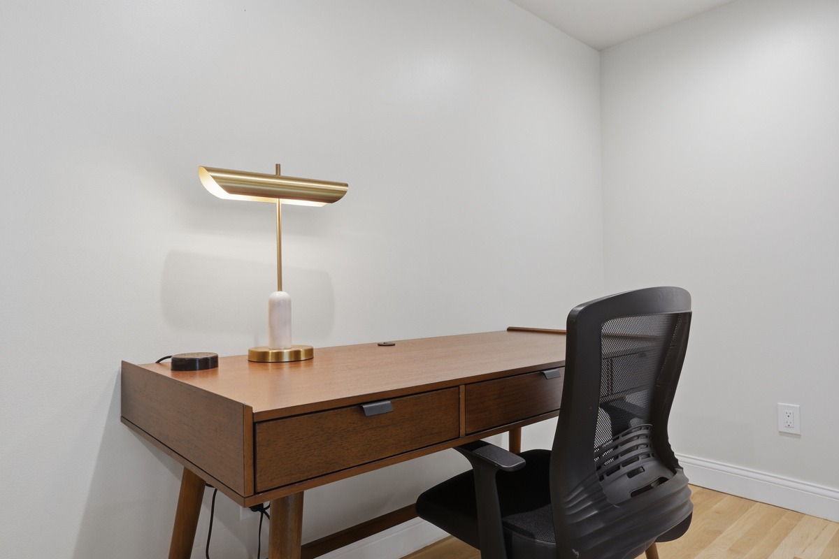 Modern, mid-century inspired workspace with a sleek wood desk, ergonomic chair, and warm accent lighting. A clean, minimalist setup designed for focus, productivity, and remote work during your stay.