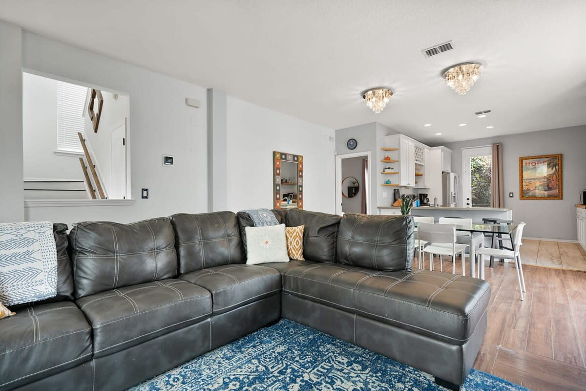 Leather sectional, a soft rug, and the dining area just beyond. Ten people fit into this house without ever feeling like ten people, which is a harder trick to pull off than most listings will admit to.