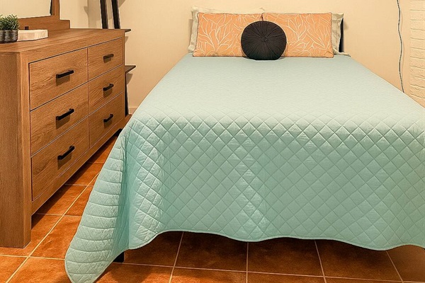 Simple and serene Full Sized bedroom with a dresser, ideal for solo travelers or kids who need their own space.
