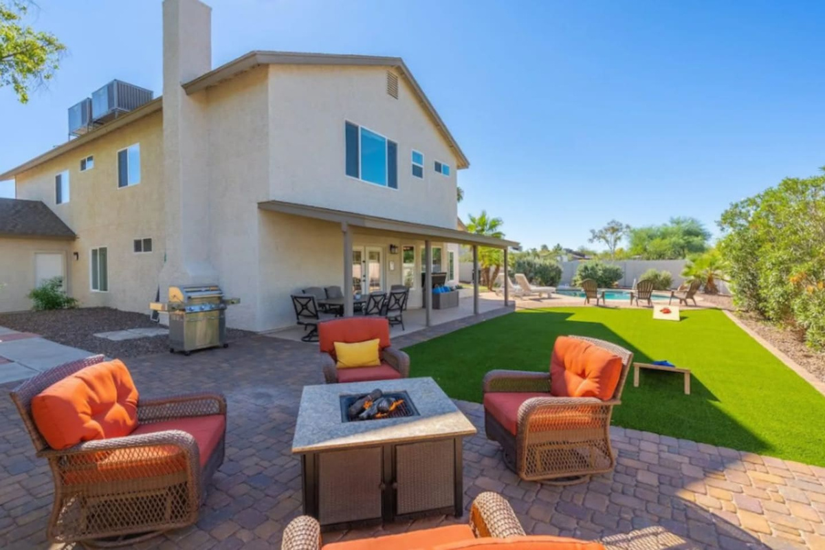 Expansive backyard oasis with firepit, manicured lawn, covered patio, and pool access.
