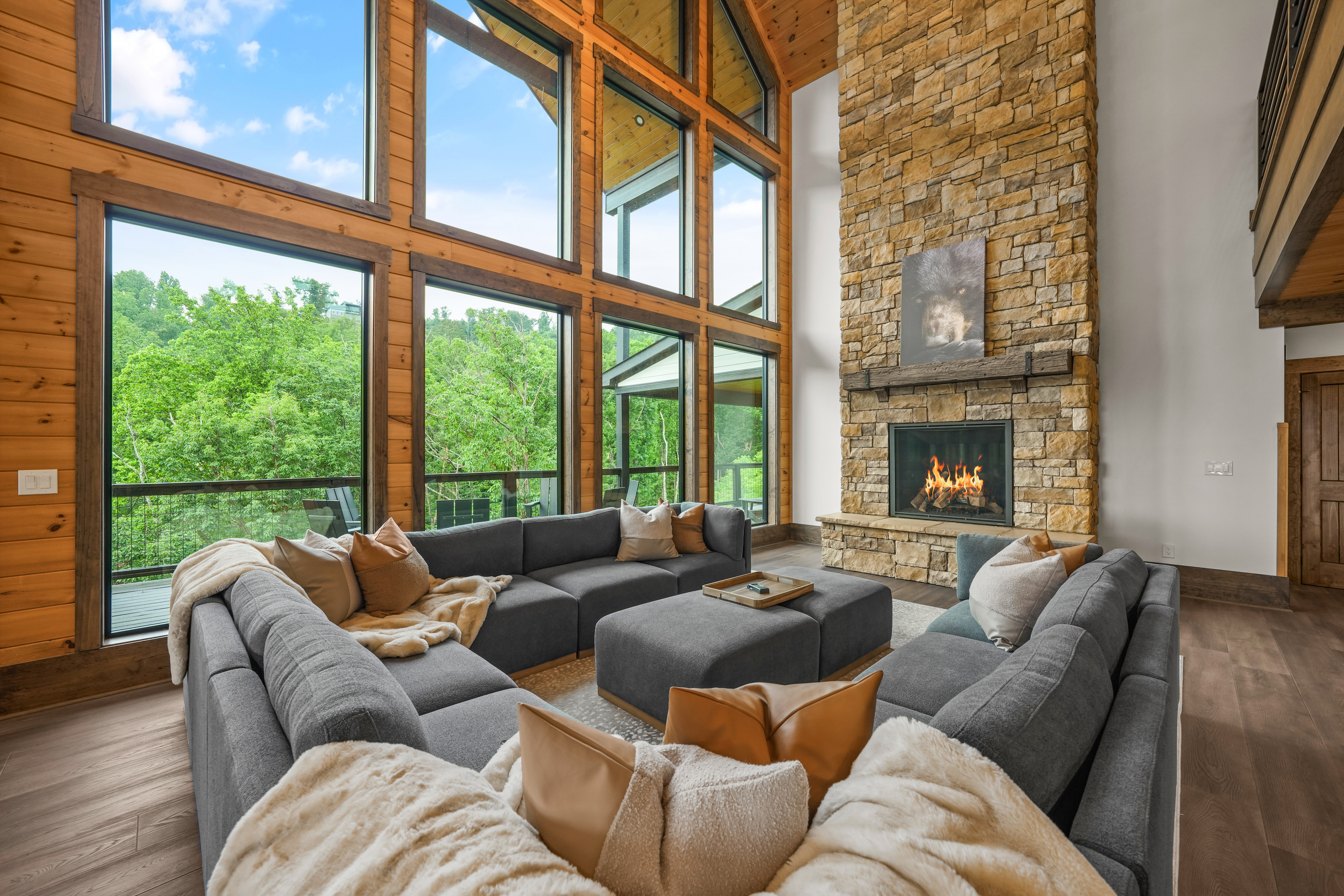 Gather beneath 30-foot vaulted ceilings surrounded by a wall of windows. Relax on the large sectional sofa beside the luxury fireplace with stunning floor-to-ceiling stone, creating a warm and unforgettable mountain lodge atmosphere.
