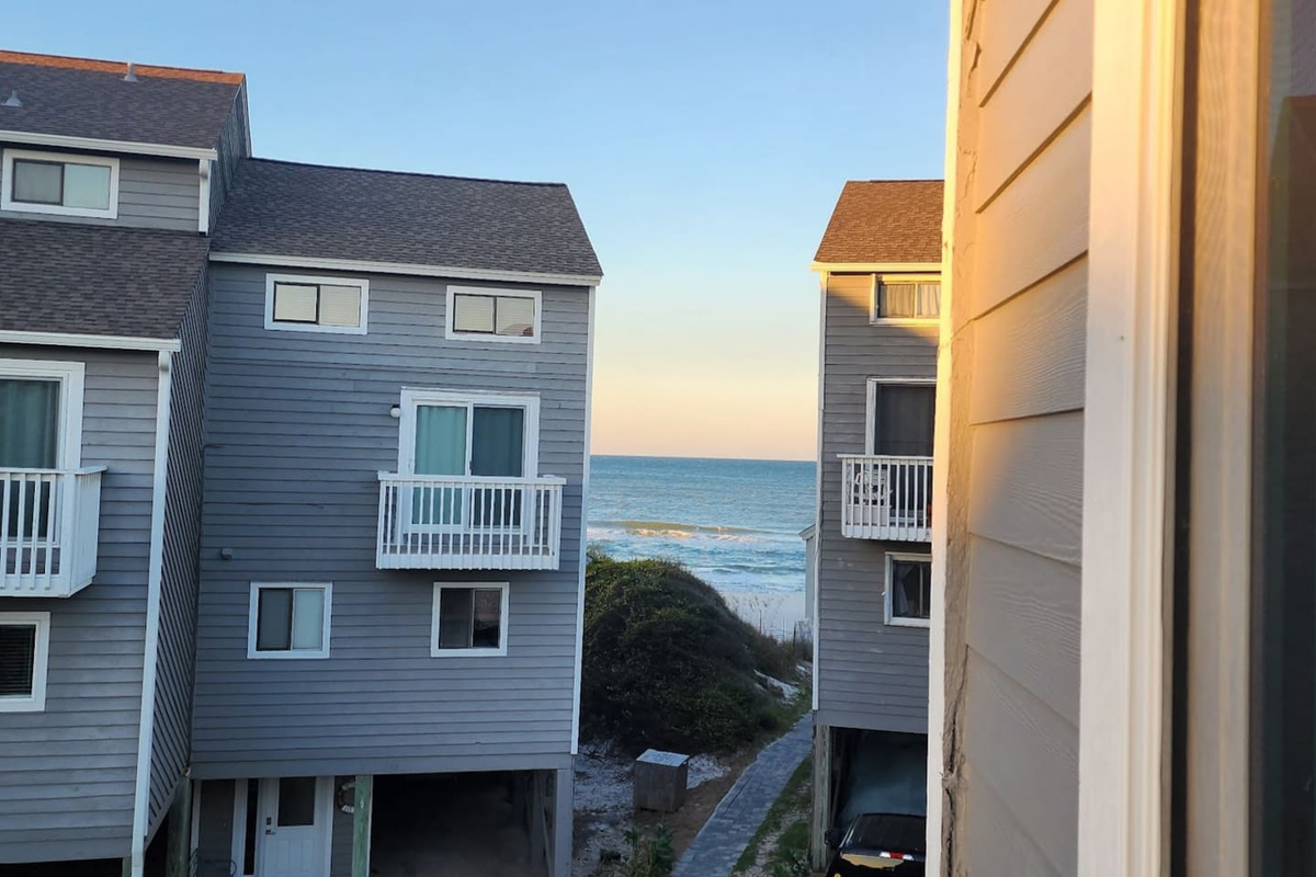 Step onto the queen bedroom balcony and the Gulf spreads out below &mdash; both upstairs suites have this view. Nobody gets the better room; everyone wins.
