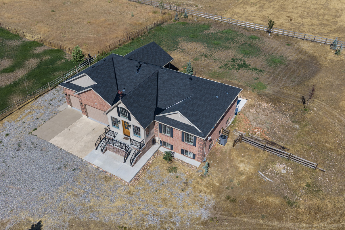 This elevated view highlights the home’s private setting, generous driveway, and surrounding open landscape.