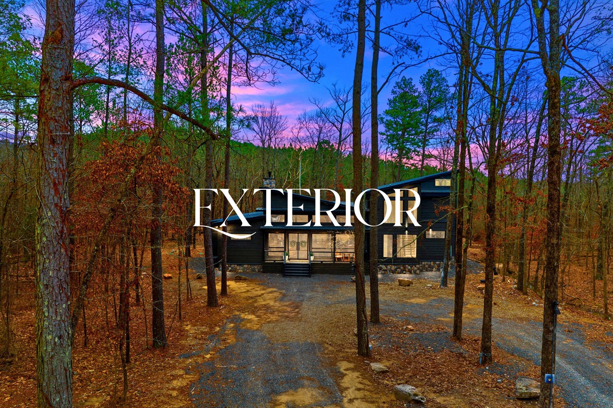 The cabin exterior stands beautifully among the pines, especially striking in the soft evening light.