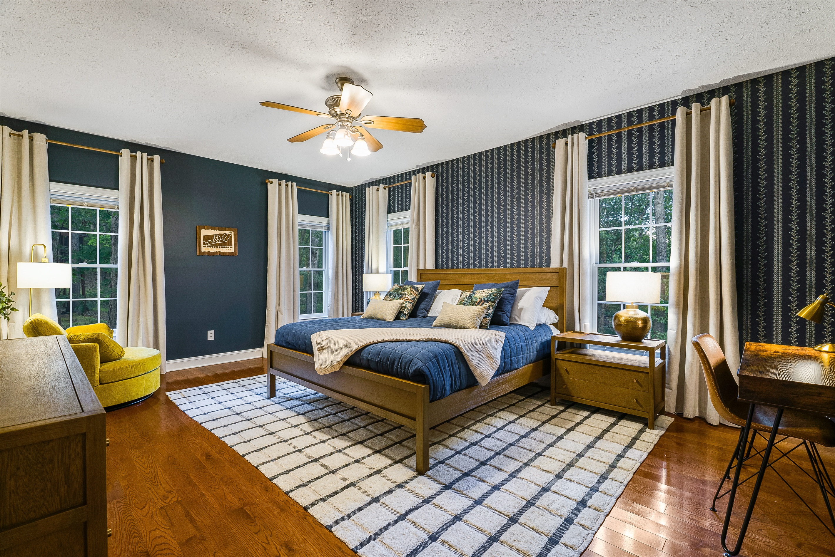 Spacious king suite with rich blue accents, stylish wallpaper, and warm wood furniture — your retreat after a day of adventure.