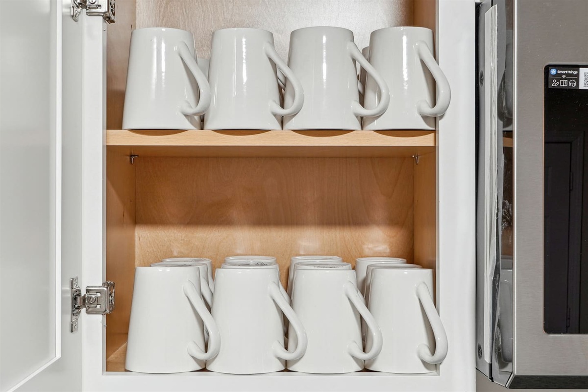 A fully equipped kitchen with a refrigerator, microwave, stove, oven, dishwasher, coffee maker, kettle, toaster, and blender. Includes plates, bowls, utensils, pots, and pans, plus four bar chairs for casual dining or socializing.
