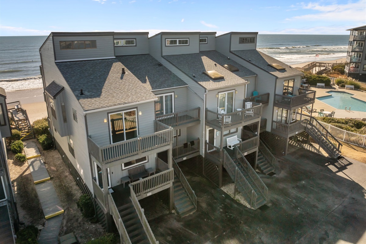 An aerial view of our home with multiple private balconies, plus easy beach access and a shared seasonal pool just steps away