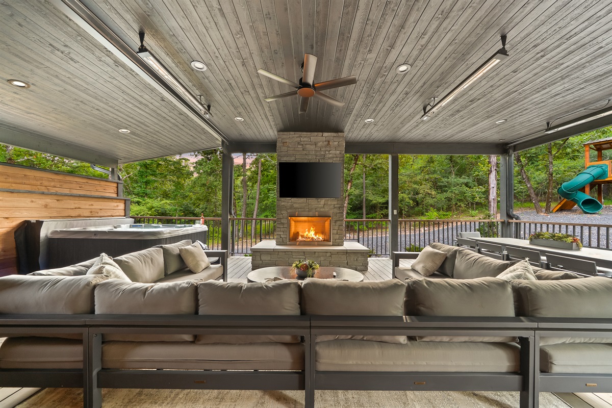 Large covered patio includes a gas fireplace, hot tub, smart TV, large spacious sectional, and outdoor dining area. Includes infrared heaters included as an extra bonus for all-weather enjoyment!