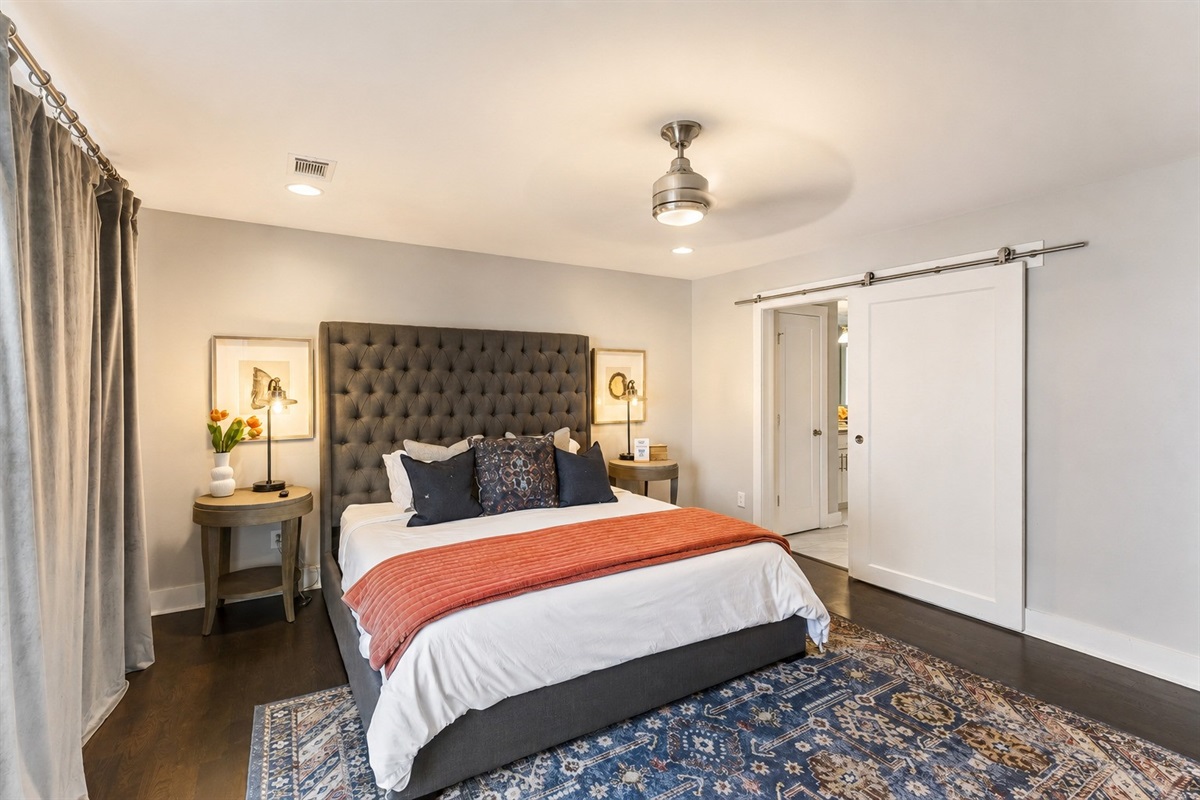 Wake up in the master suite &mdash; king bed with a charcoal tufted headboard, barn door, and private balcony doors to greet the morning.