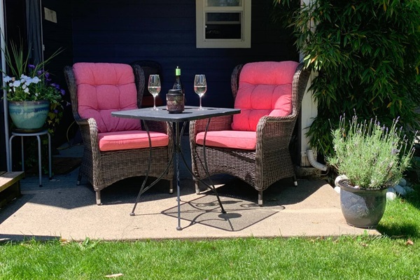 Private patio with luxurious high back furniture beside a zen garden with a bubbling fountain overlooking the forest of Thetis Lake.