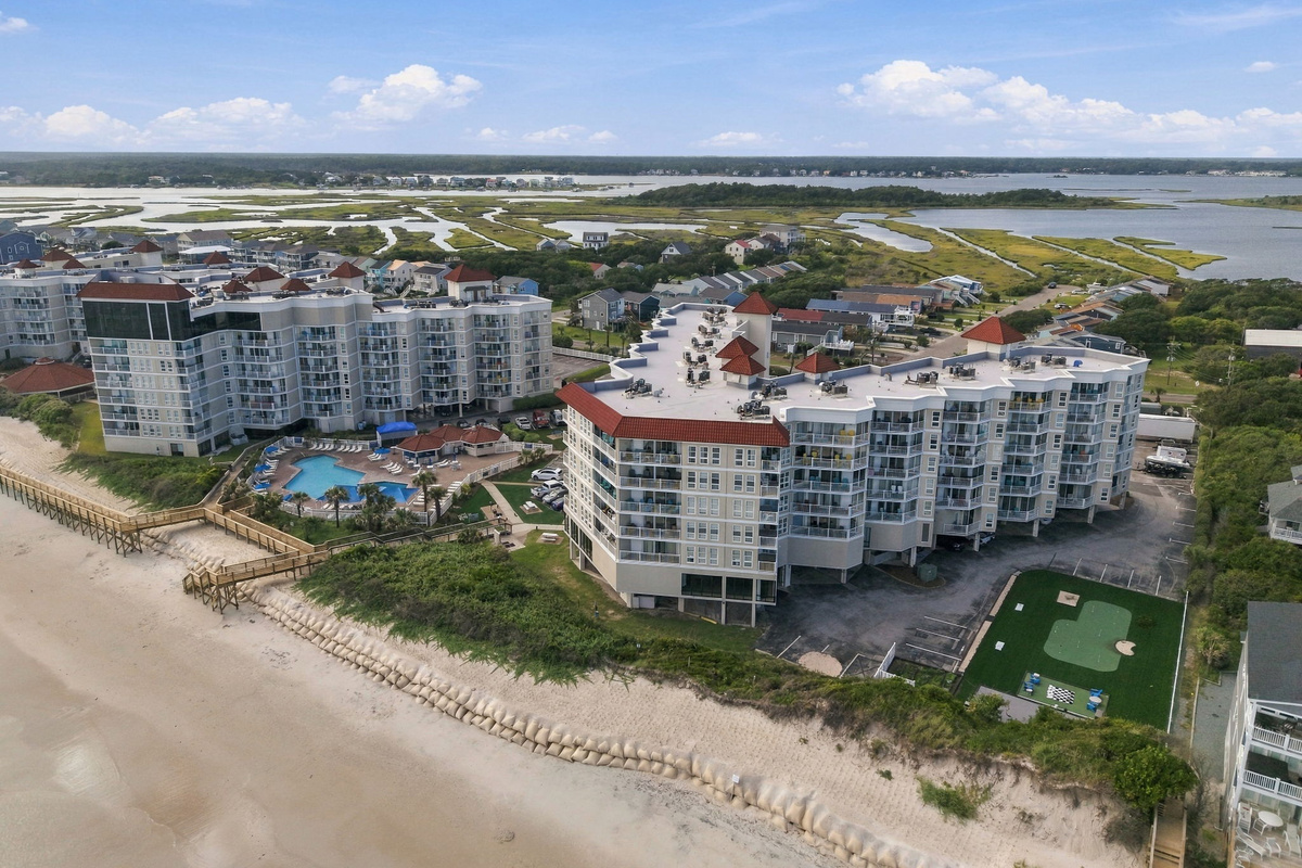Wide aerial view of the oceanfront resort grounds, capturing the main building, private dunes, and surrounding shoreline.