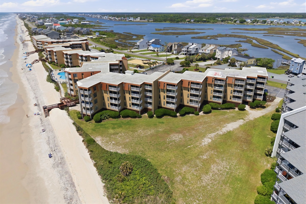 Expansive aerial view of Topsail Dunes featuring beachfront buildings, parking, and outdoor recreation areas

