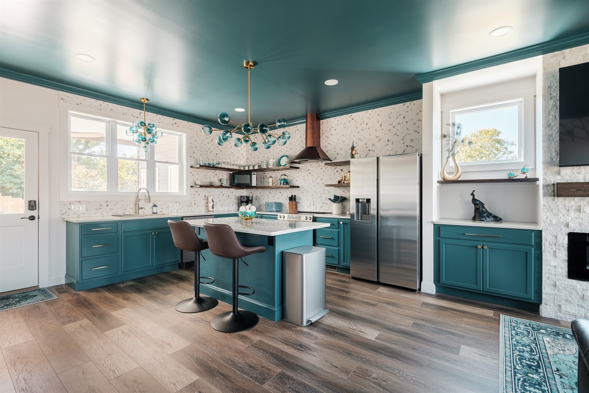 Large windows flood the space with natural light, highlighting the open shelving, designer fixtures, and rich flooring throughout.