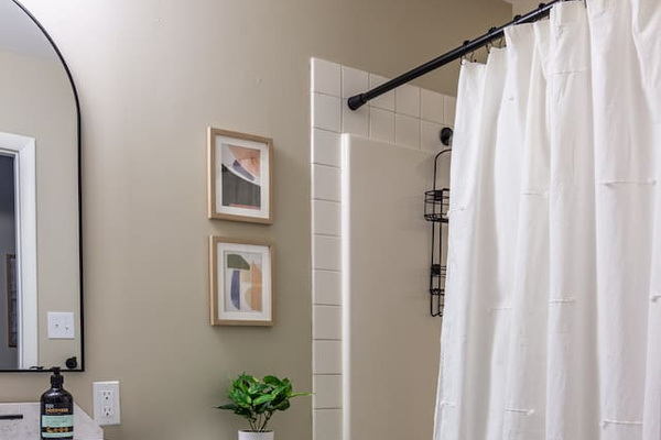 Curated art and a fresh green accent turn the everyday shower into a small daily luxury.