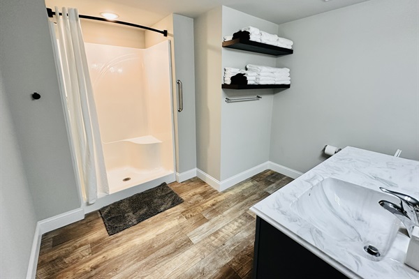 Large bathroom with full shower and plenty of towels.