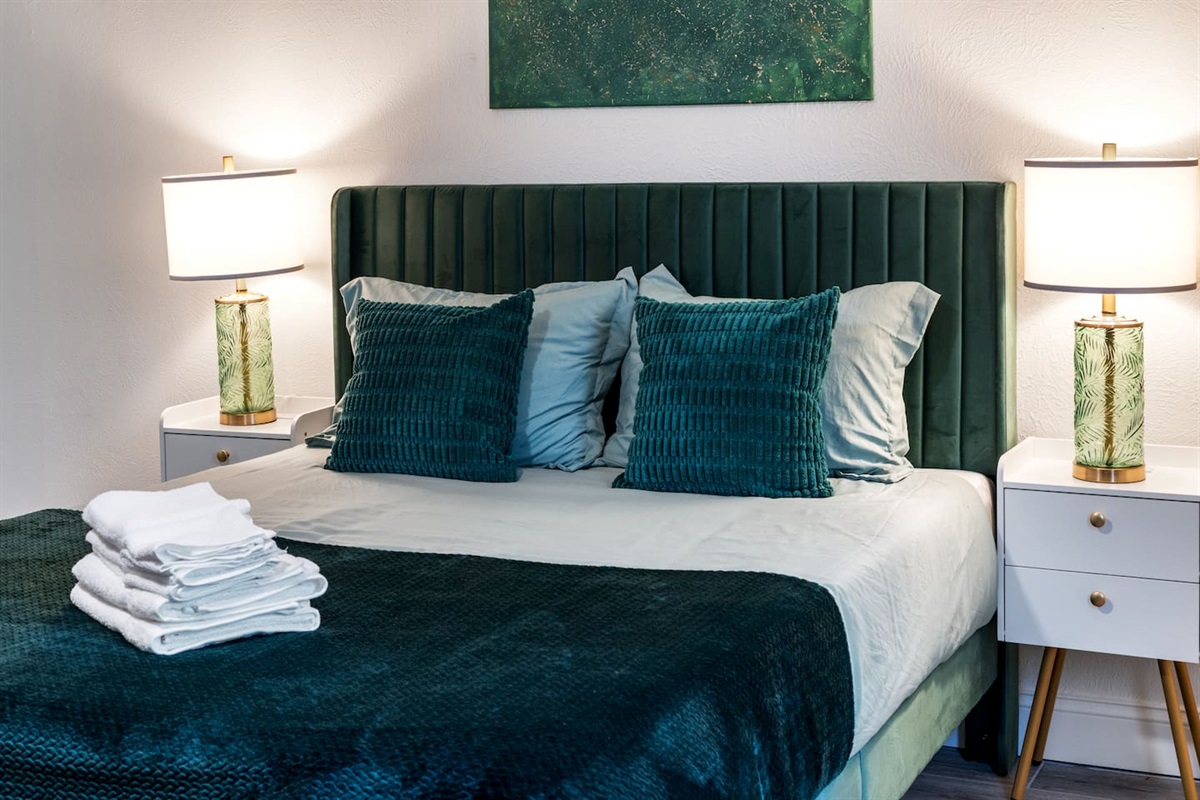 Stylish bedroom with luxe emerald accents, plush bedding, and ambient lighting—designed for a chic and restful retreat.