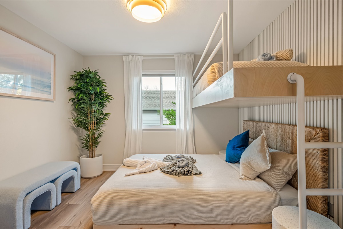 Spacious bunk bedroom with cozy queen bed below and twin bunks above — great for families.