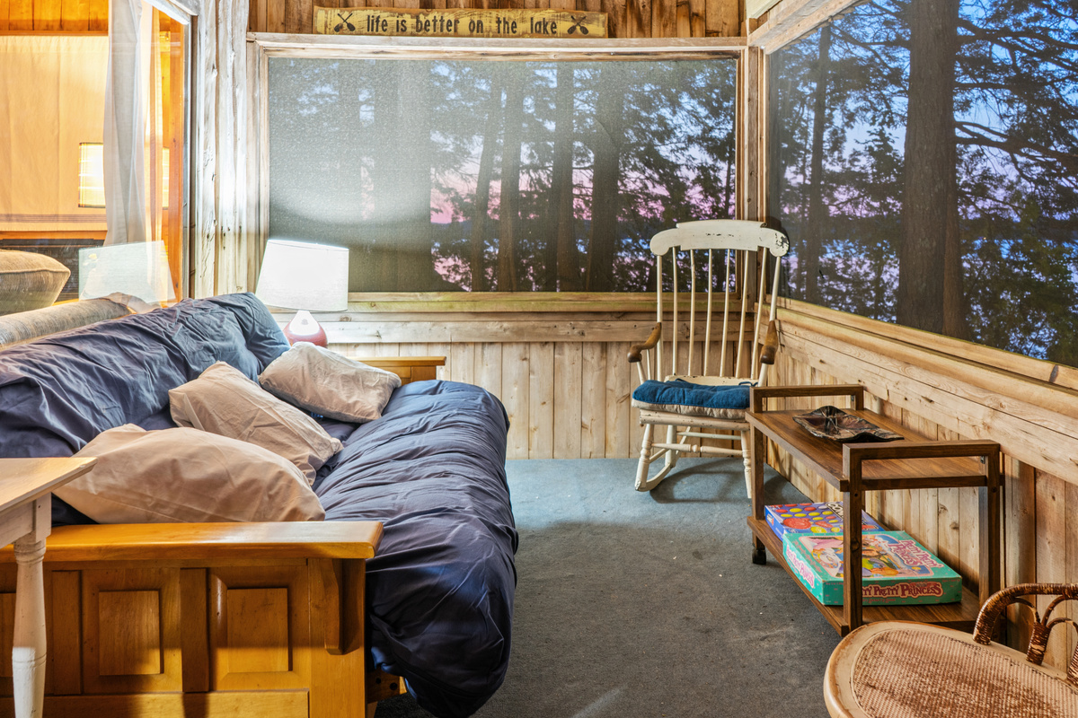 Screened porch configured as a cozy sitting area at Loonrise Point! Enjoy vibrant sunset skies over Beech Hill Pond in Otis, ME from the futon sofa or rocking chair. Versatile porch space converts easily between lounge and bed!