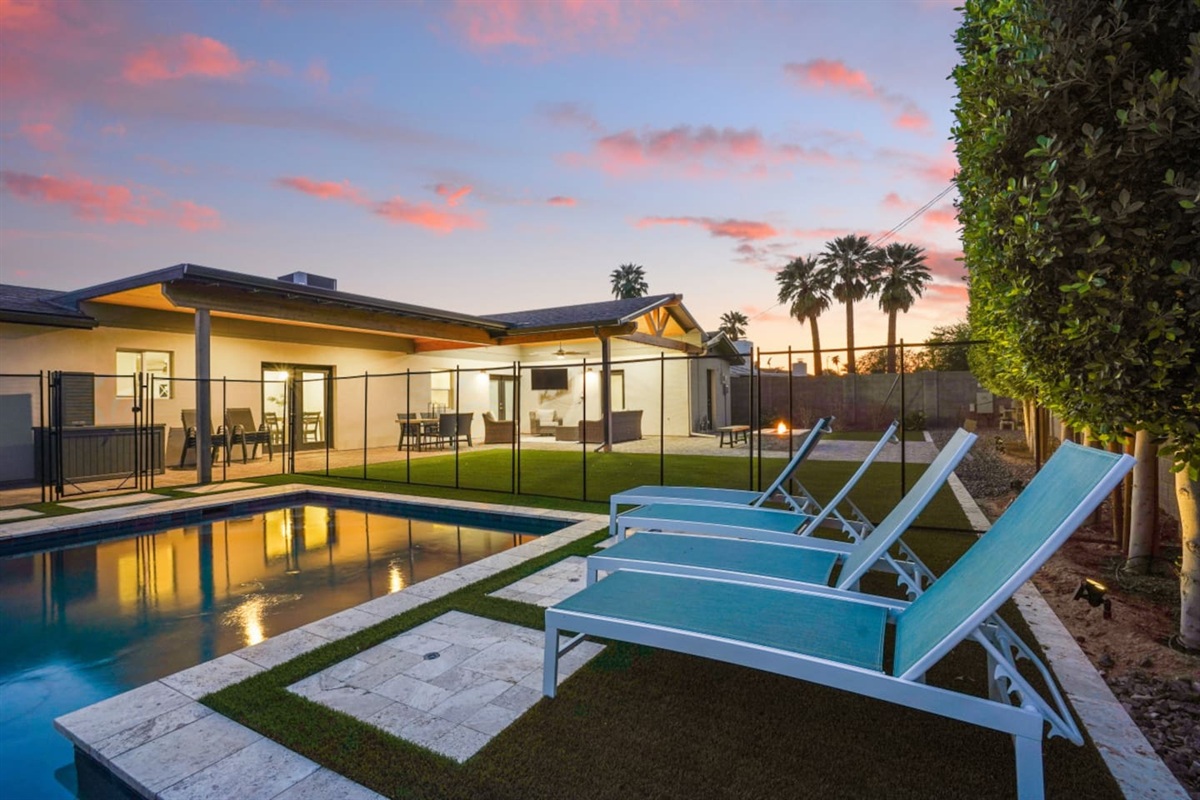 Private backyard pool with lounge chairs, umbrella shade, fire pit seating, and a bright outdoor space 