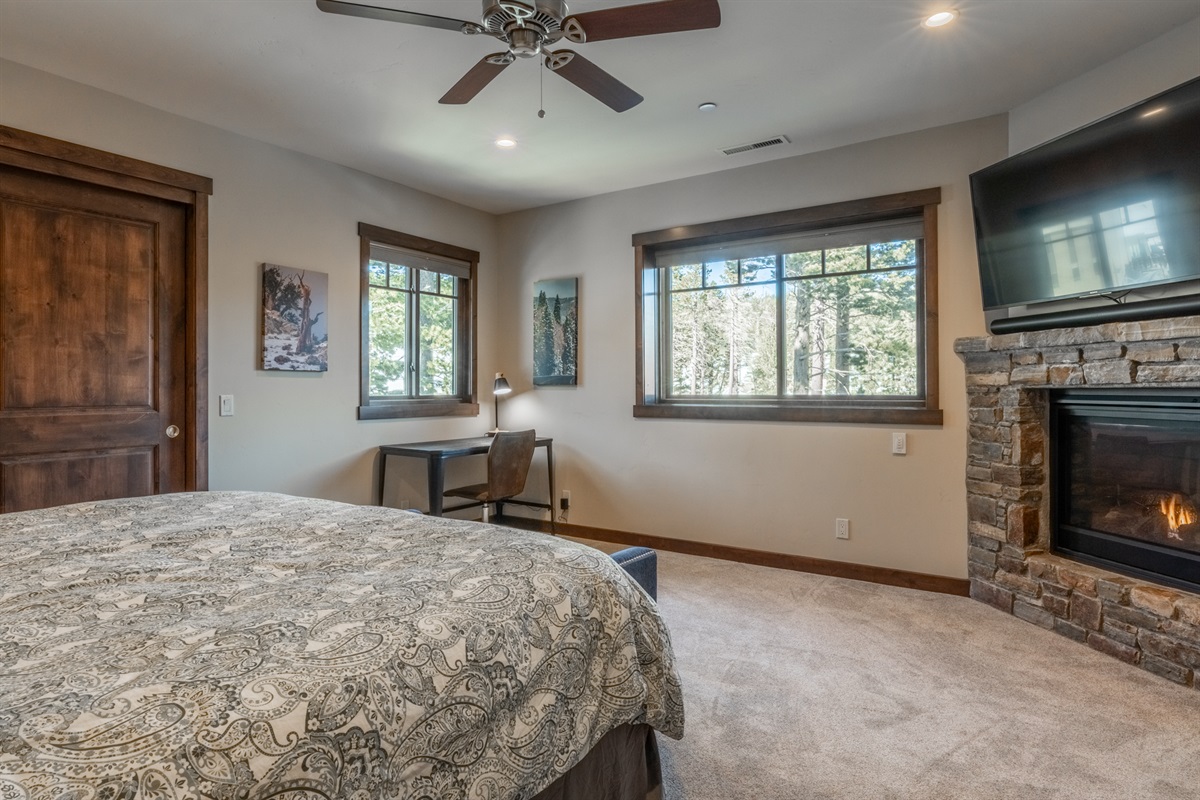 Retreat to the calming blue hues of the primary bedroom, complete with a plush king bed, cozy fireplace, dedicated workspace, and a large smart TV. Soaring windows flood the space with light and frame sweeping views of Canyon Lodge—your personal haven of c