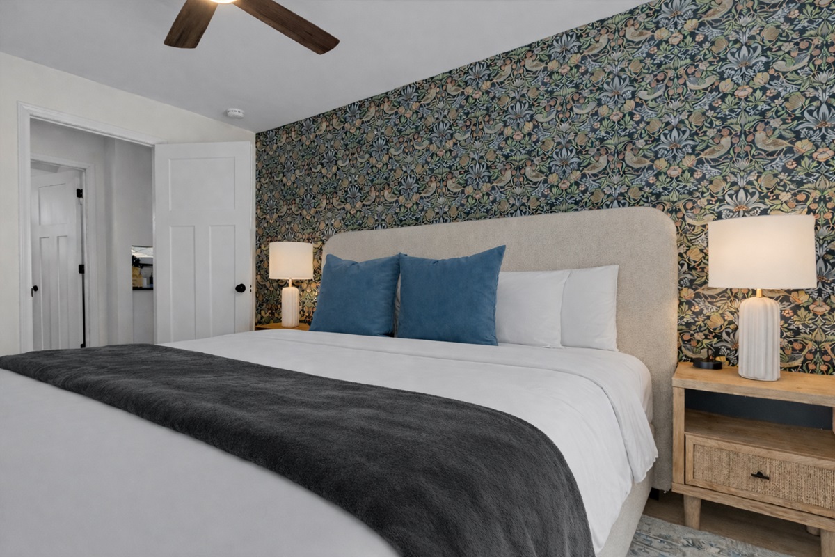 Comfortable, thoughtfully designed bedroom with a plush bed, ceiling fan, soft lighting, and a stylish accent wall for a relaxing retreat.