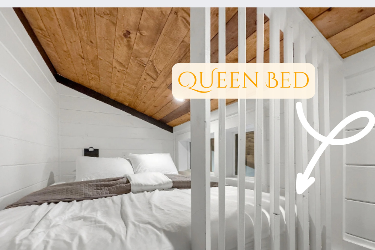 Slip into comfort in our charming loft bedroom, featuring a plush queen bed nestled under a rustic wood-paneled ceiling. It's your private haven for a restful night's sleep.