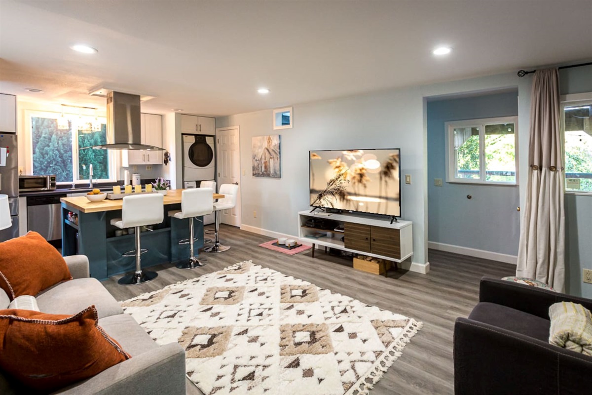 - Bright living space with flat screen TV and open flow to the kitchen area  
- Breakfast bar seating creates a perfect spot for casual meals or drinks  
- Soft neutral tones paired with modern accents give a welcoming feel  
