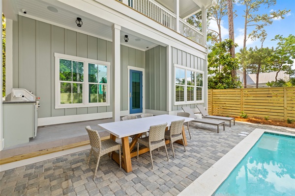 Table, chairs, and loungers in private backyard oasis