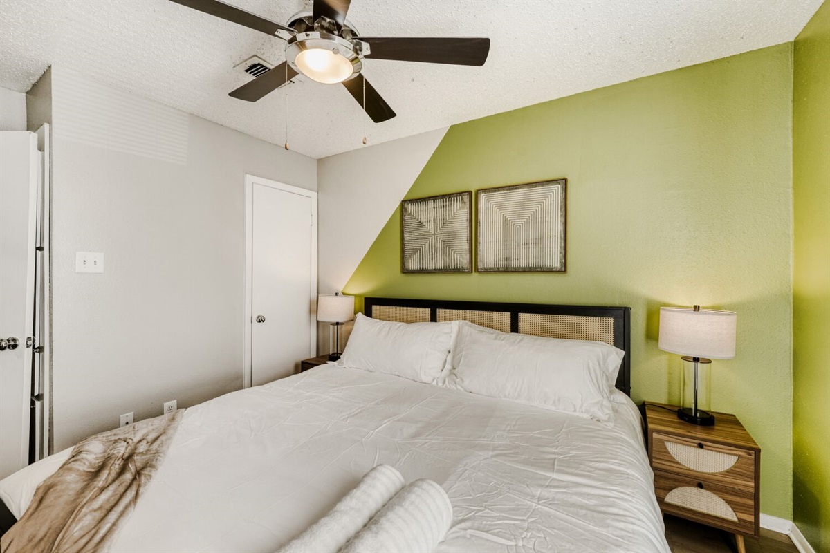 Cozy bedroom with a green accent wall, modern lighting, and a comfortable king-sized bed.
