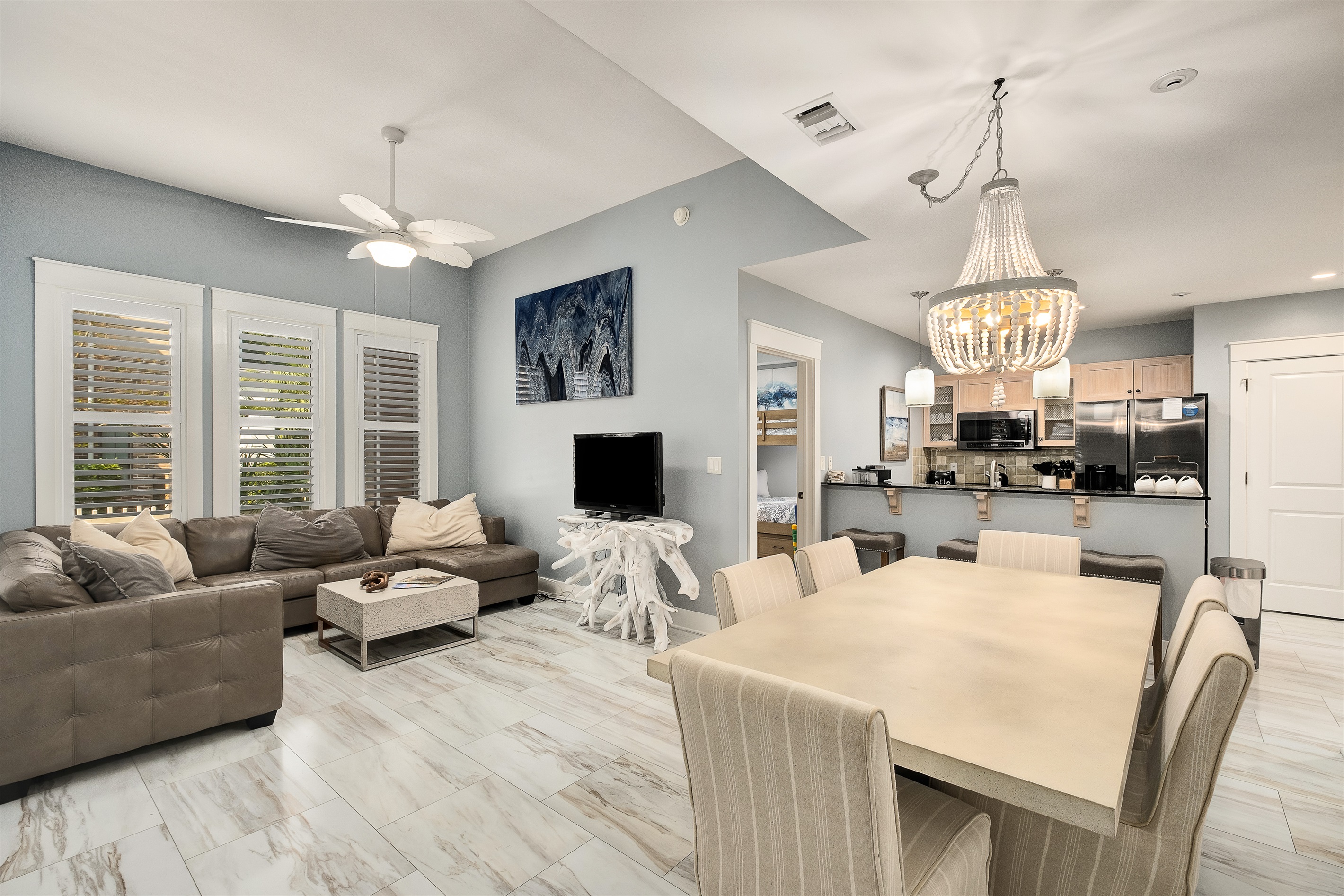 Modern living area with plenty of seating and natural light streaming through the shutters. The dining space flows seamlessly into the kitchen, making it easy to entertain while cooking.