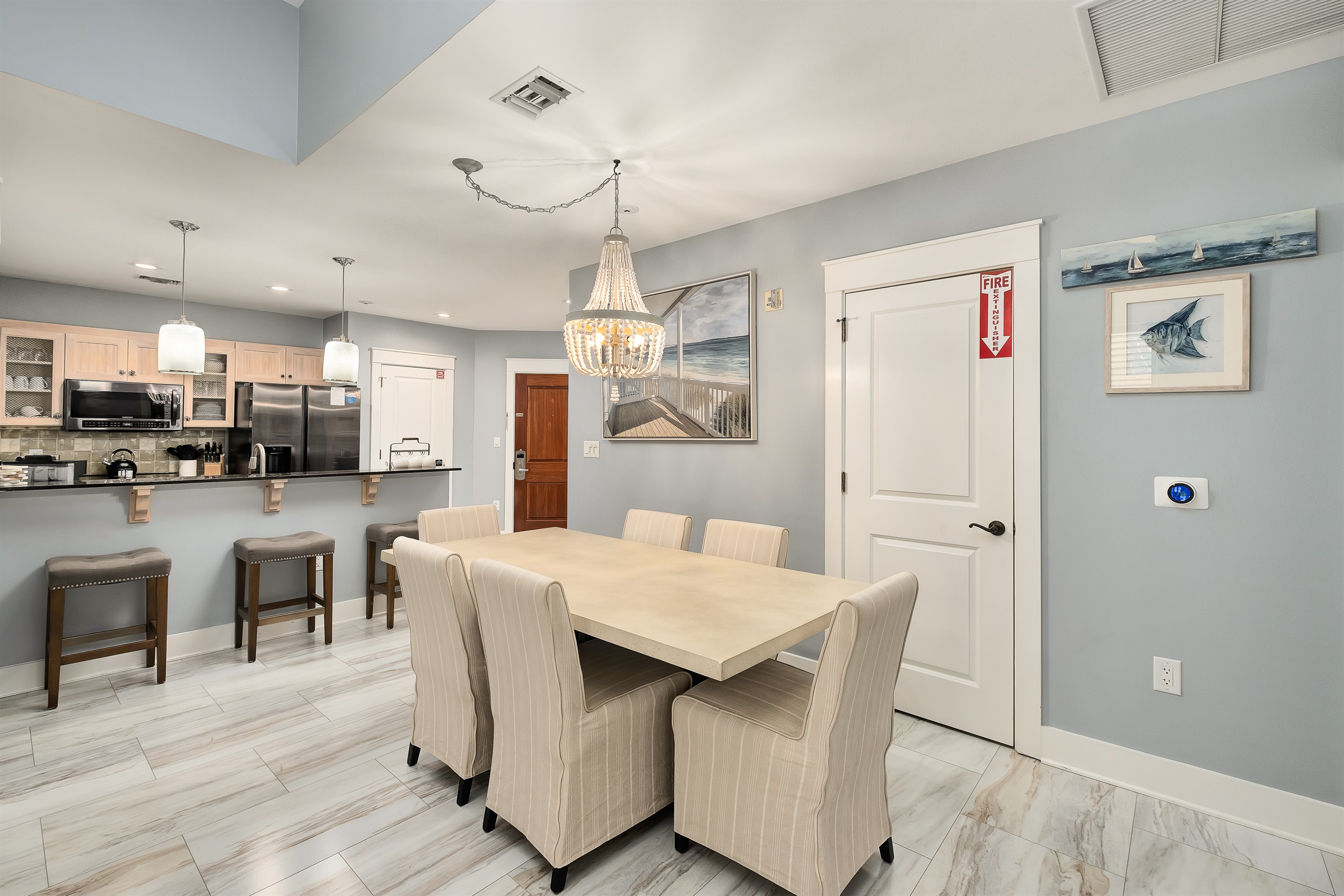 Gather around the spacious dining table beneath the elegant chandelier, just steps from the kitchen for a smooth flow of meals and conversations. Perfect for group dinners or a quiet night in.