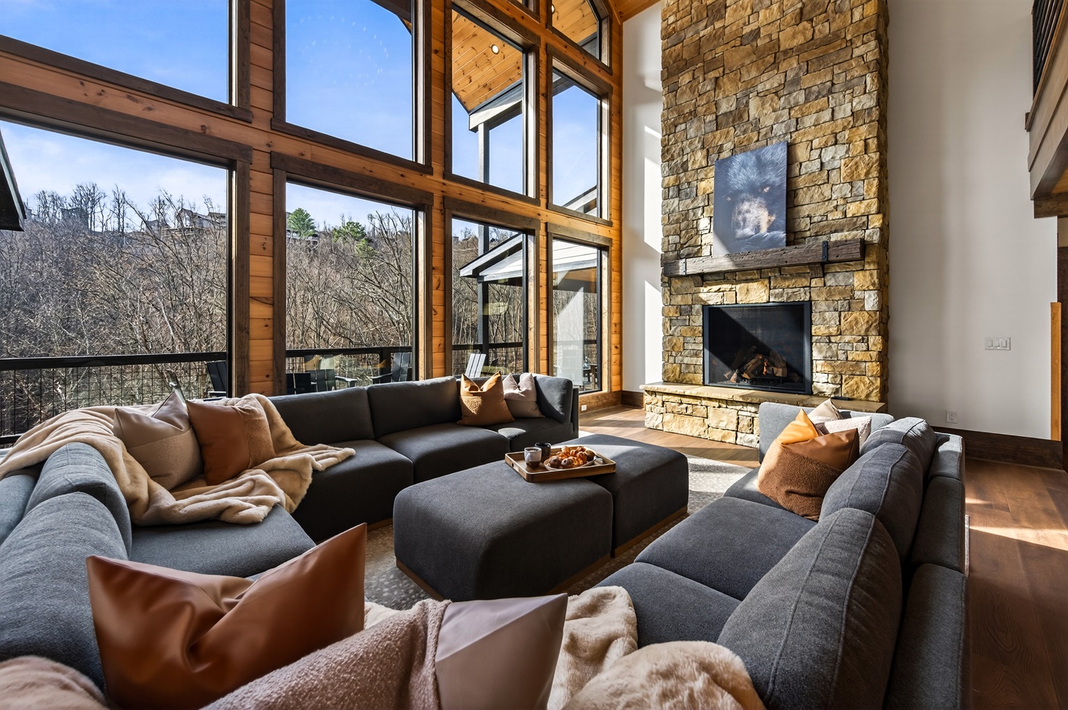 Gather beneath 30-foot vaulted ceilings surrounded by a wall of windows. Relax on the large sectional sofa beside the luxury fireplace with stunning floor-to-ceiling stone, creating a warm and unforgettable mountain lodge atmosphere.
