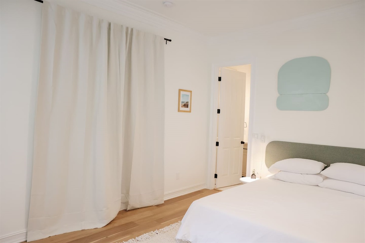 The downstairs bedroom is off of the foyer hallway with glass french doors. Thick blackout curtains provide privacy to room guests.