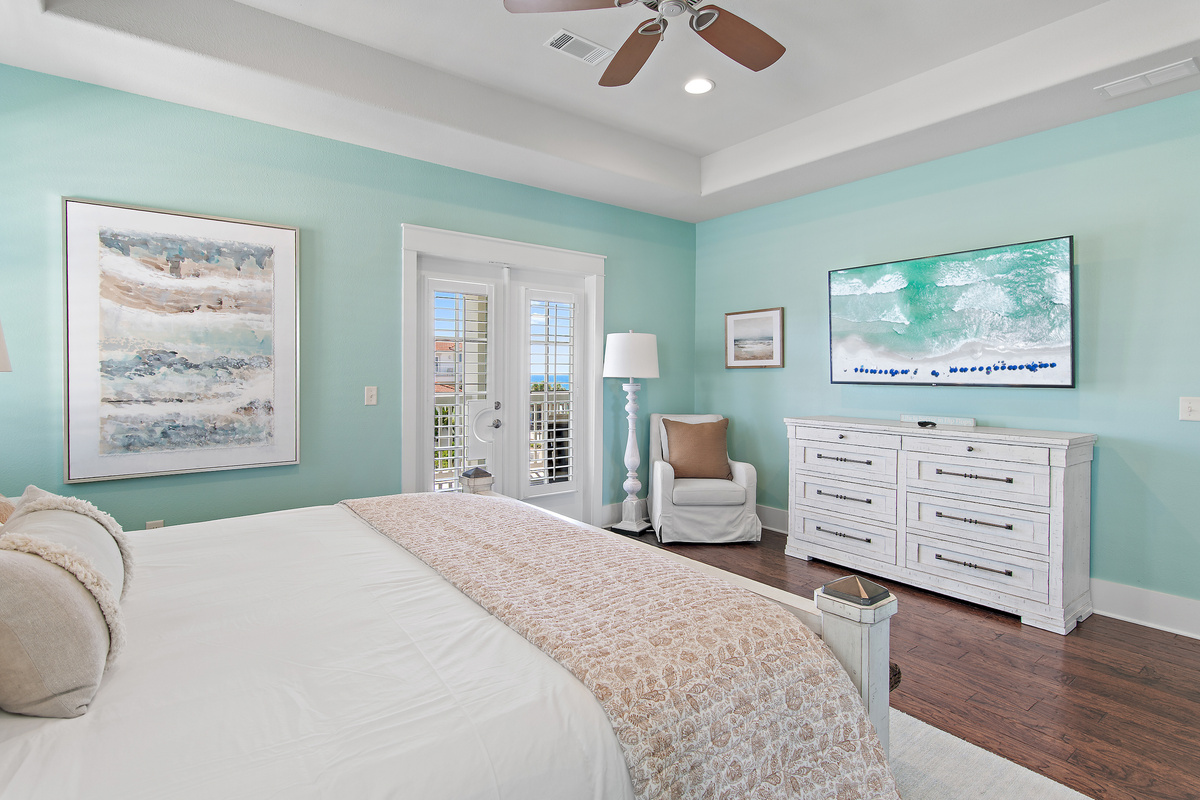 Relax in this spacious coastal bedroom, featuring a comfortable king bed, soft beach inspired décor, and plenty of natural light.
