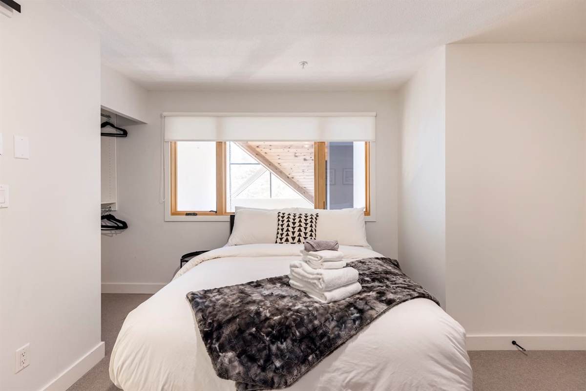 Upstairs bedroom looks out to the exterior windows and the downstairs living space.