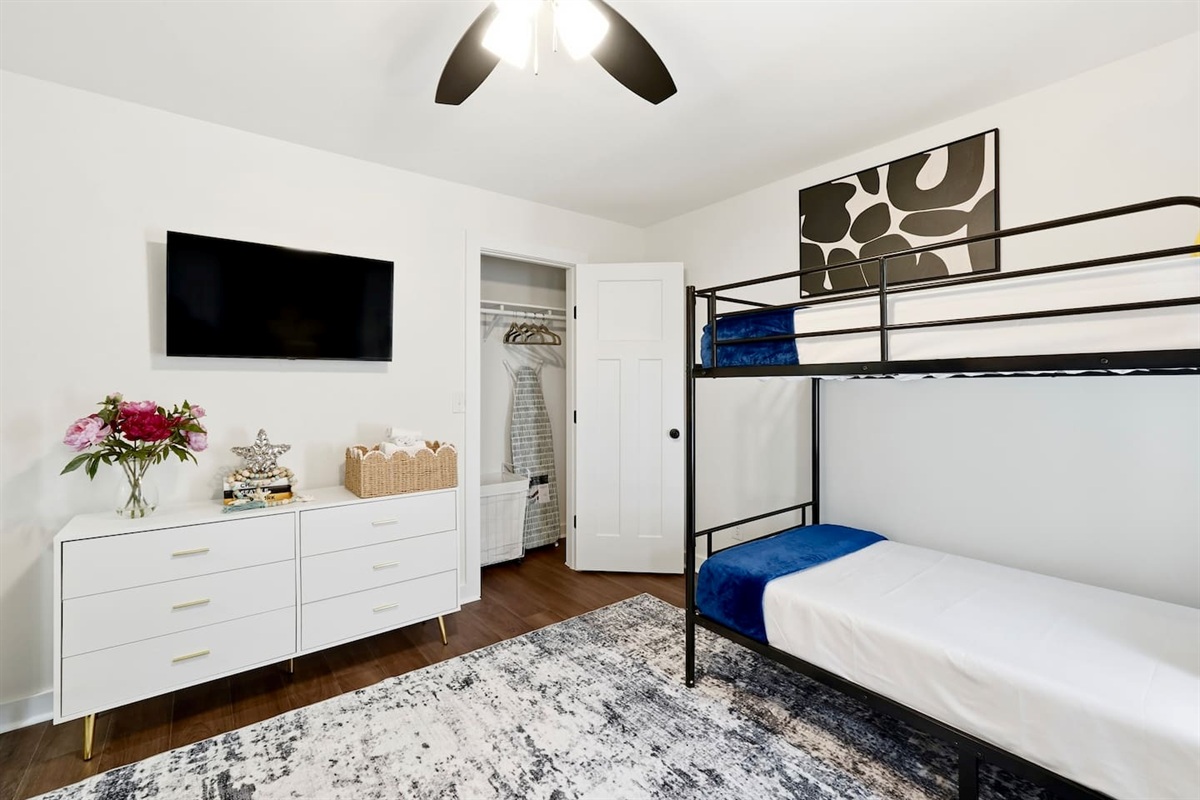On the second level, you’ll find a cozy bedroom featuring two bunk beds, each equipped with comfortable blankets and a Roku-powered TV. This welcoming room is the first one you’ll encounter as you walk up the stairs.