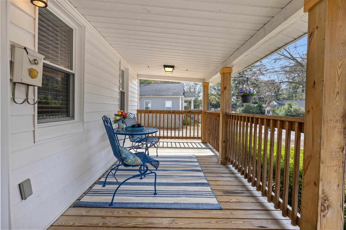 The covered porch features a bistro table and seating for two