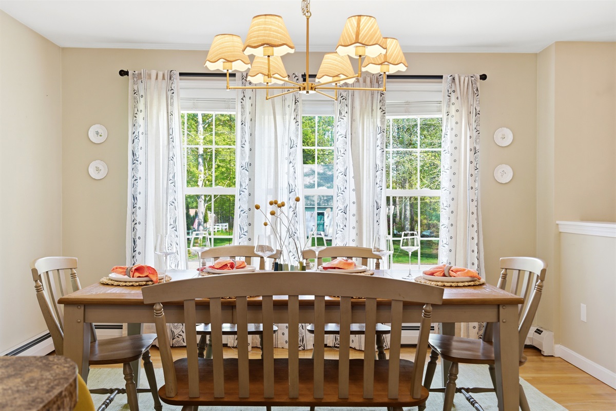 A bright and spacious dining area filled with natural light from surrounding windows, beautifully set with elegant cutlery for a welcoming dining experience.