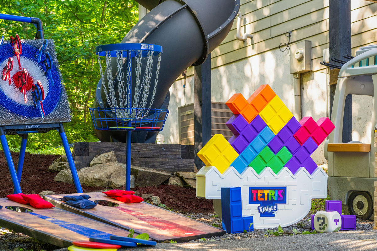 A playful little world waiting below the slide — colorful games, kid-sized imagination, and plenty of “just one more round” energy tucked into the trees