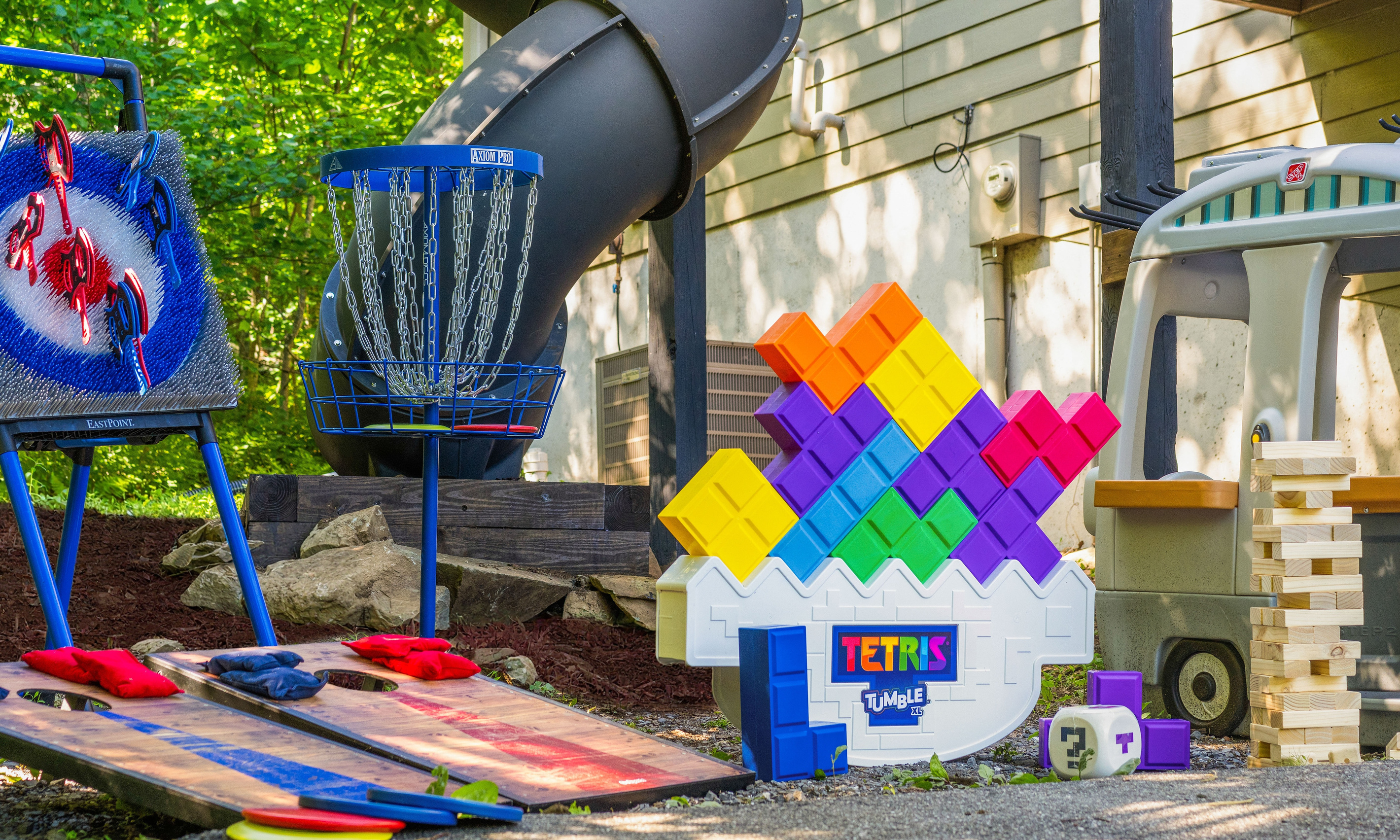 A playful little world waiting below the slide — colorful games, kid-sized imagination, and plenty of “just one more round” energy tucked into the trees