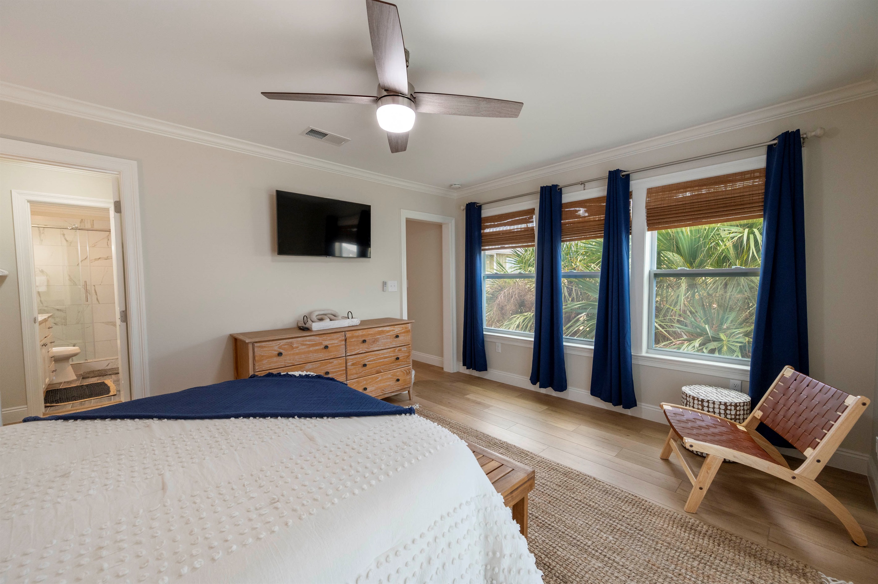 A cozy bedroom with a TV, wooden dresser, and lush views offers comfort and relaxation for guests.