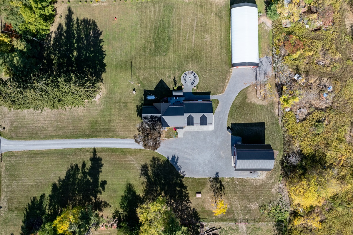 Aerial view showcasing the spacious Finger Lakes property with charming farmhouse and classic red barn