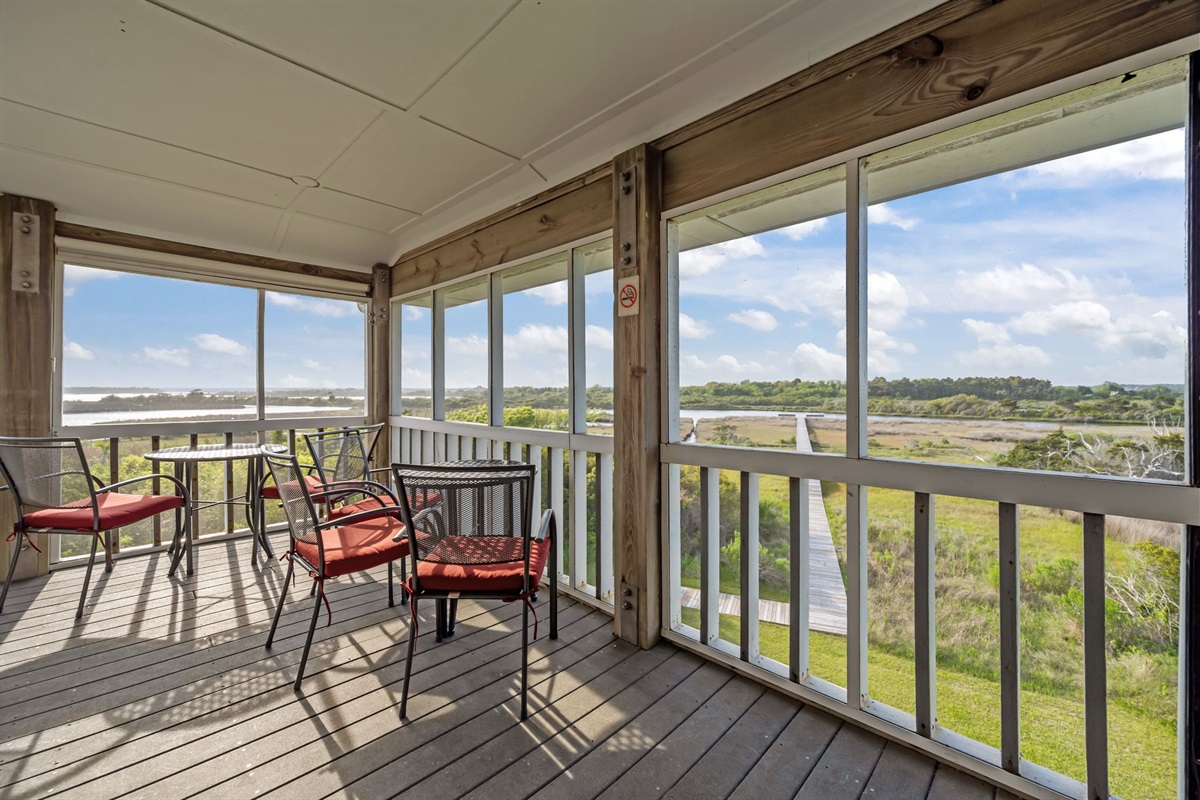 Panoramic screened-in views overlooking the marsh and boardwalk leading to the water