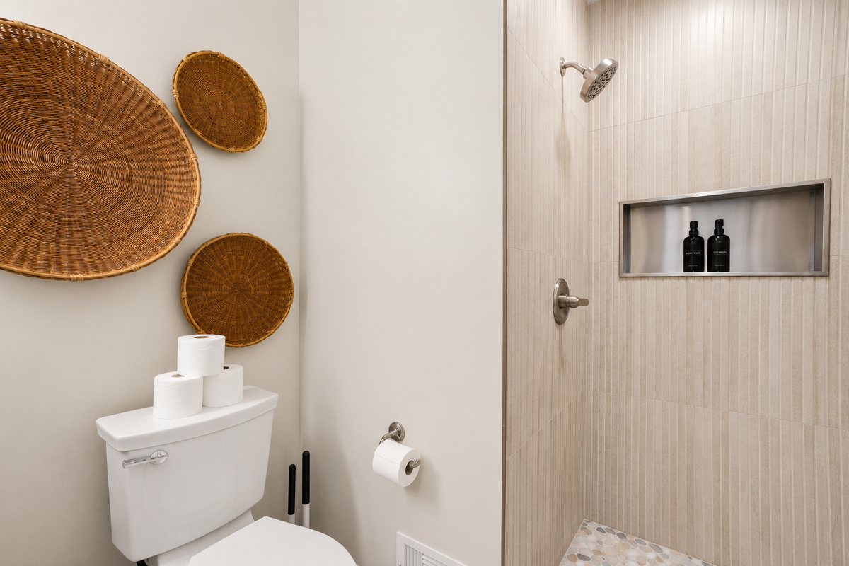 Modern bathroom with elegant stone tile walk-in shower, built-in niche, and warm woven accents. Clean, spa-inspired design with a bright, calming, hotel-like feel.